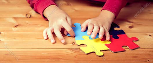 Banner, An autistic child`s hands play colorful jigsaw puzzle symbol of public awareness for autism spectrum disorder. World