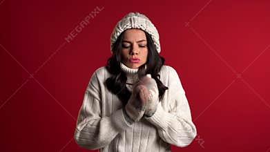 Warmly dressed woman shaking from low temperature in knitted hat and mittens.