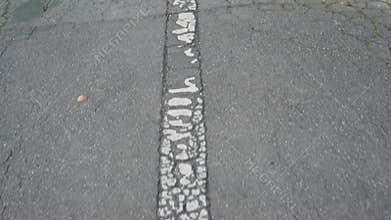 Shabby white arrow on cracked old gray asphalt. Road marking of the direction of movement