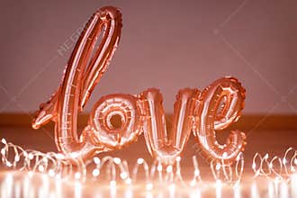 Rose gold foil balloon in the form of a word Love with light garland. Happy Valentine day. Word love letters from the inflatable