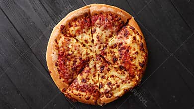 Fluffy pepperoni pizza in american style placed on rusty old black wooden table