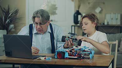 Grandpa and a teenage boy are constructing a toy car