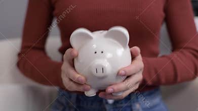 Woman is shaking piggy bank