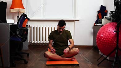 Man stretches finishing workout at home and look at fitness bracelet