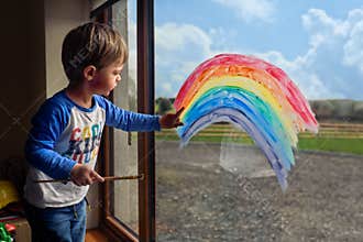 Boy drawing rainbow on the window