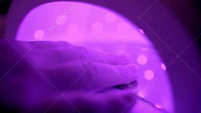 Manicured nails in UV lamp. Rays cure gel polish.