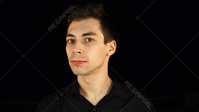 Blue-eyed man says no and nods his head on black background.