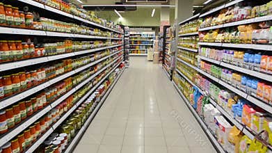 Products on shelves in chain supermarket. Shopping in local grocery store. Tinned goods, cans and bottles on display for sale in