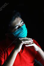 Dramatic portrait of a boy wearing medical face mask looking out deep in thought.