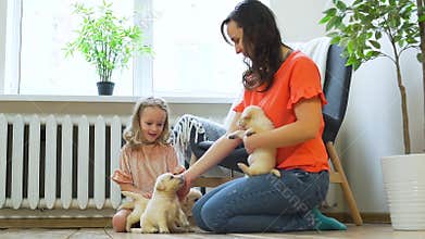 Woman with Daughter Playing with Puppies at Home