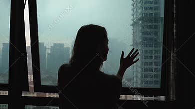Silhouette sad loneliness woman touch glass window at rain day