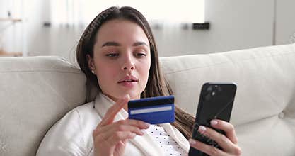 Happy young woman holding credit card using mobile payments