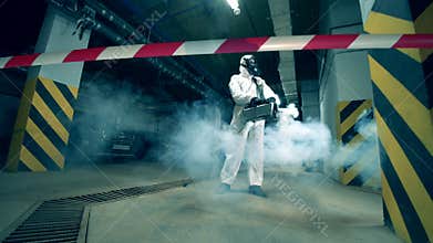 Man in hazmat uses machine to disinfect restricted area.