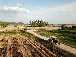 Tractor move at path in paddy field.Harvester park at background.