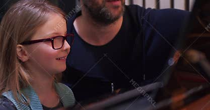 Piano class with teacher and kid learning. Kid learning to play piano from teacher. Little girl learning piano lesson.Side
