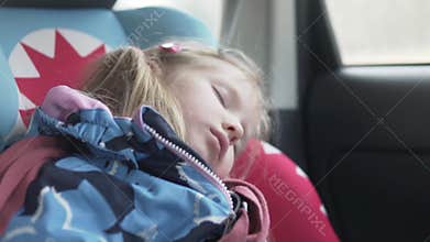 The baby sleeps in a car seat in the car