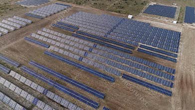 Aerial footage of solar panels on a field, the shot is moving in a half circle