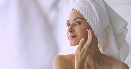 Happy beautiful lady hydrating skin, enjoying daily skincare routine.