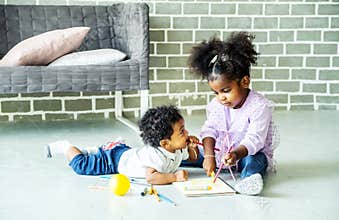 Cute black african american little girl and boy drawing book on floor indoors,  African people - Children