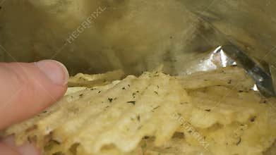 Macro sliding shot of hand taking crisps from the package. Probe lens view.