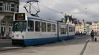 Light rail tram traveling on rails down a street road with historic buildings in
