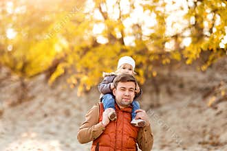 Girl sitting on dad shoulders on walk in fall. family weekend in nature