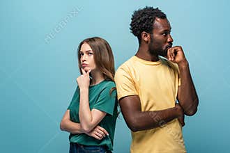Interracial couple standing back to back on blue background