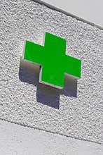 Green cross logo of Pharmacy sign in street