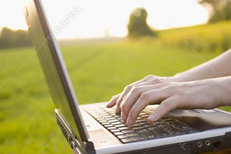 Typing on a laptop outside