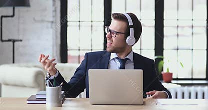 Overjoyed young funny businessman listening to energetic rock music.