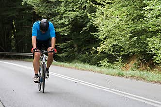 Tired road cyclist going solo uphill with copyspace