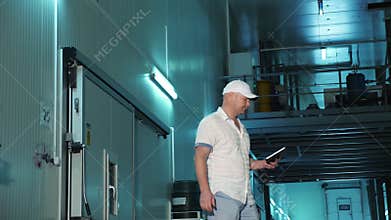 Storage. warehouse. male employee with digital tablet works in warehouse. walks past special large refrigerating