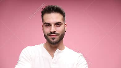 young casual man in white shirt posing on pink background
