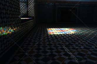 Dark room decorated with tiles and mosaic while light enters from a window