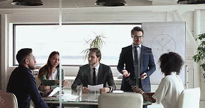 Leader in formal wear conducting brainstorming meeting with multiracial colleagues.