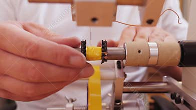 Hand making electronic component using coil winding machine - close up