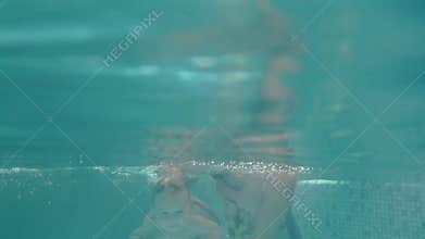 Little child to swim underwater in water baby class in the pool