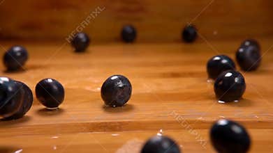 Delicious large blueberries are falling onto the wet wooden surface