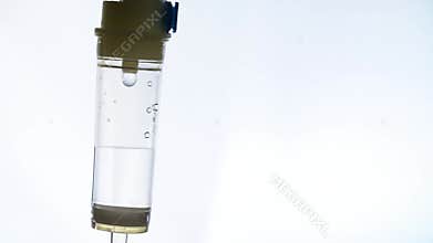 Closeup of the drug dripping inside of plastic tank of the dropper in flashlight ambulance signal