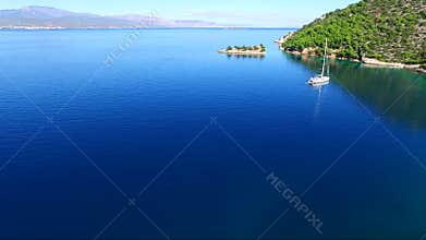Aerial view of Siderona bay, Corinthia, Greece, on a lovely bright day in a calm blue and turquoise sea, with sailing boat