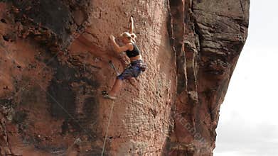 Young woman climbing an extreme difficult rock