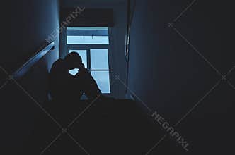 Silhouette Sad young man sitting at the stairs in the dark, Depression and anxiety disorder concept, Life problems, illness,