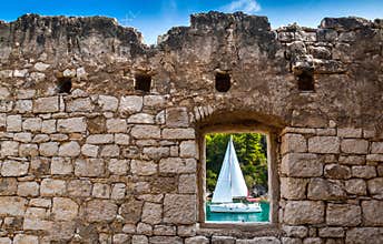 View through old stone window atsailing boat