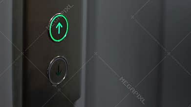 Young female pressing up button in elevator, modern office building, house