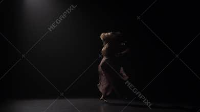 Sophisticated girl dancing at studio against black background. Slow motion