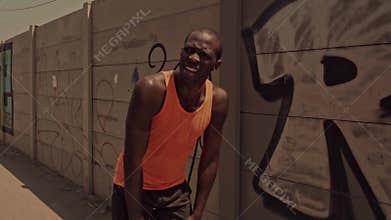 tired and exhausted black afro American professional runner man breathless after hard urban running workout leaning cooling off