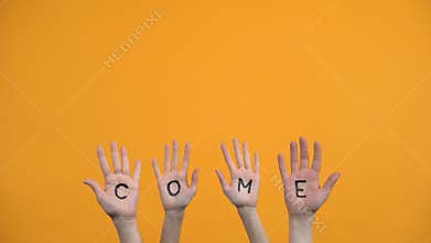 Come written palms on orange background, activist hands, project presentation