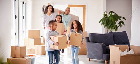 Smiling Family Carrying Boxes Into New Home On Moving Day