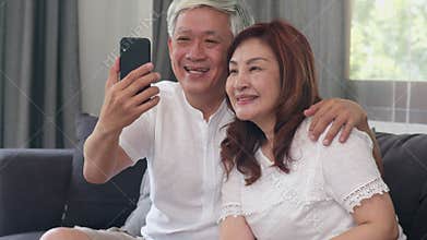 Asian senior couple video call at home. Asian Senior Chinese grandparents, using mobile phone video call talking with family