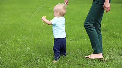 First steps baby boy with help mother. Slow motion